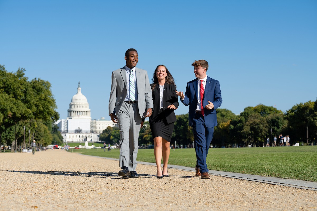 Three students walking outdoors near the U.S. Capitol building in Washington, DC.