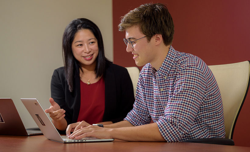 Professor and student viewing laptop