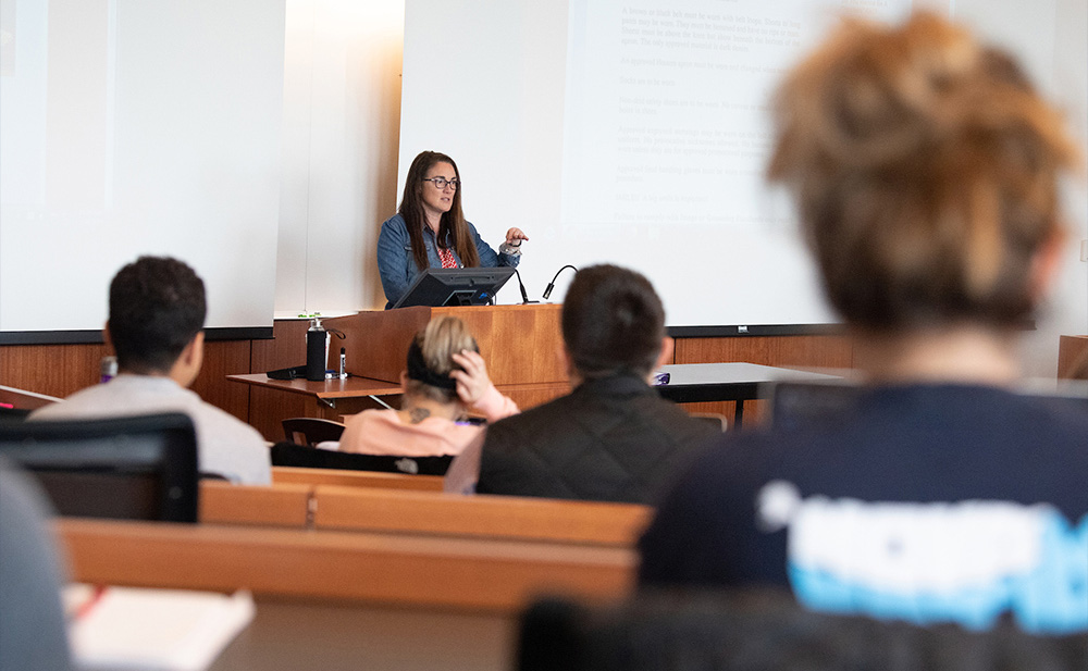 Professor Ann Juliano stands at a podium addressing a class of JD students.